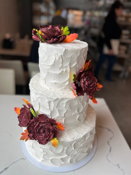 3 tier weddiing cake with burgundy roses and fall themed leaves