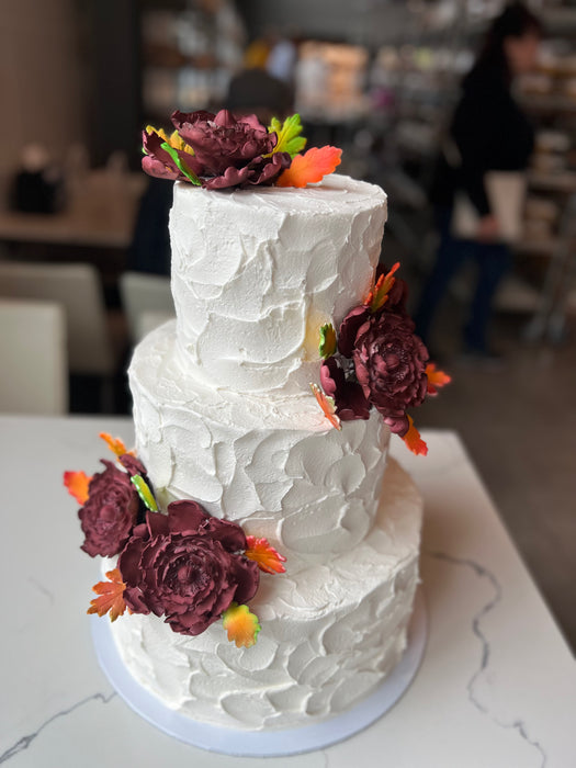 3 tier weddiing cake with burgundy roses and fall themed leaves