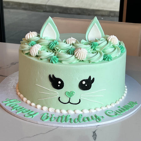 kitty round cake with green and white icing. child or adult birthday