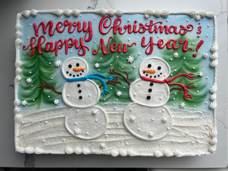 Christmas cake with snowmen, trees, and 'Merry Christmas Happy New Year' text.